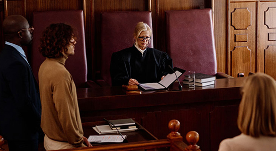 "A judge in a courtroom surrounded by people."